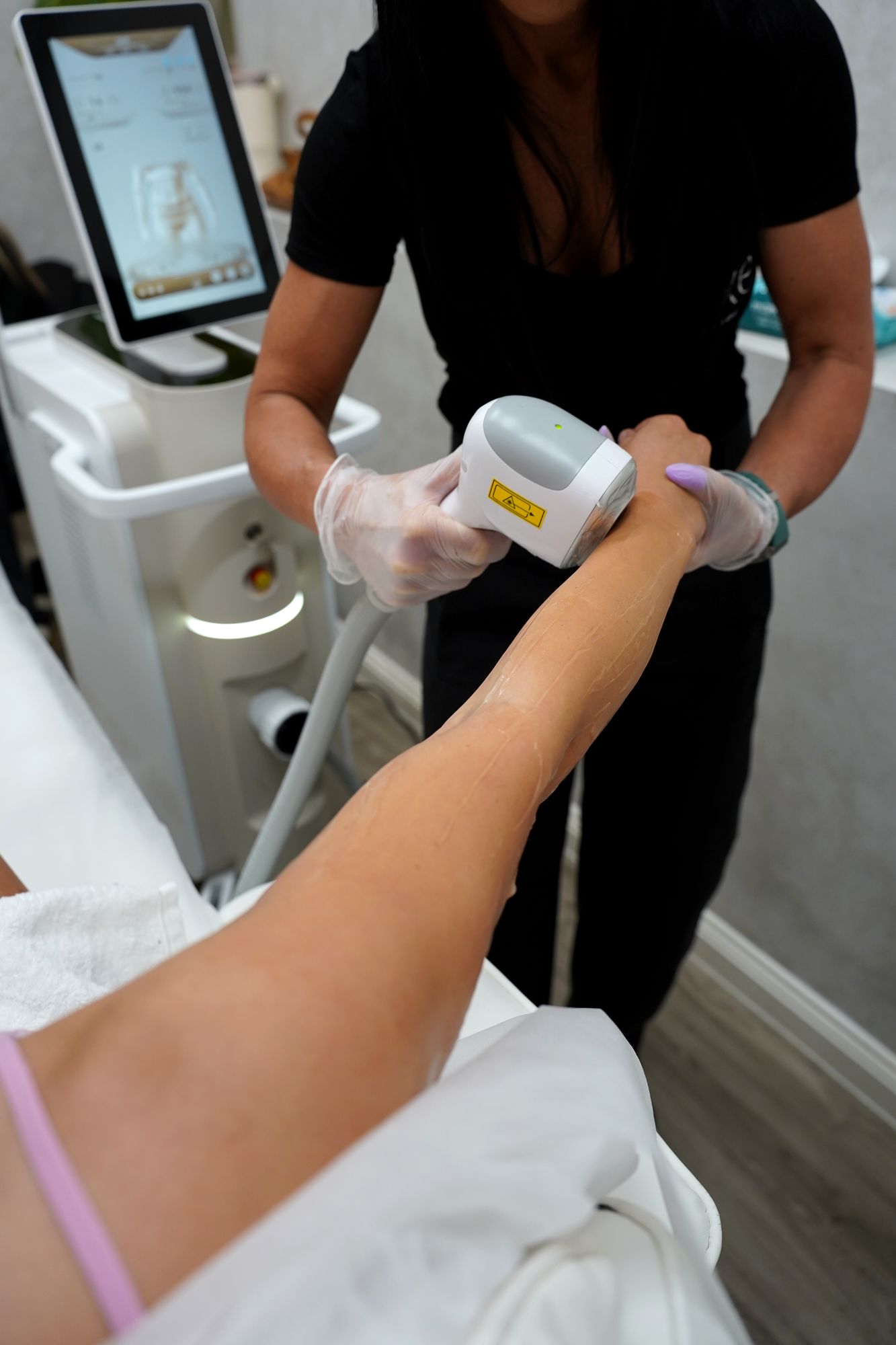 Sharon treating a client's leg beside the Skyn Lux laser