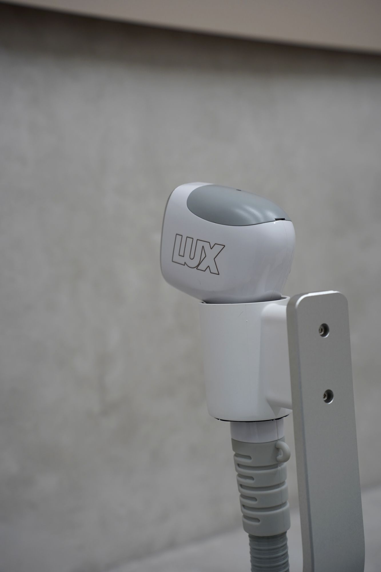 The Skyn Lux laser handpiece resting on its holder
